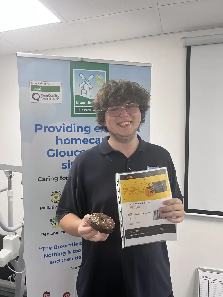 Zane in Broomfield care uniform, holding his halford's voucher